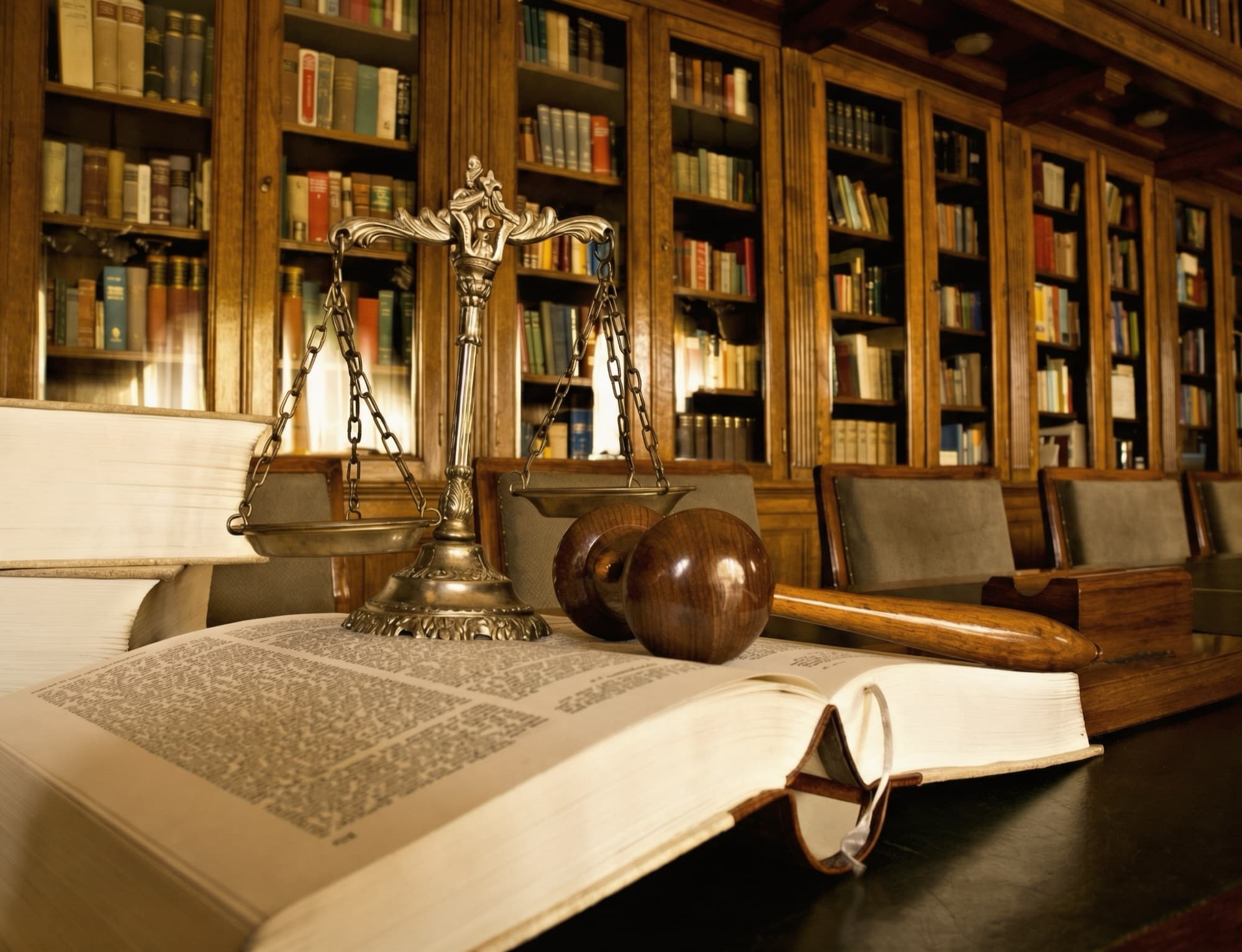 A law book and judge's gavel sits open on a table in a law library.